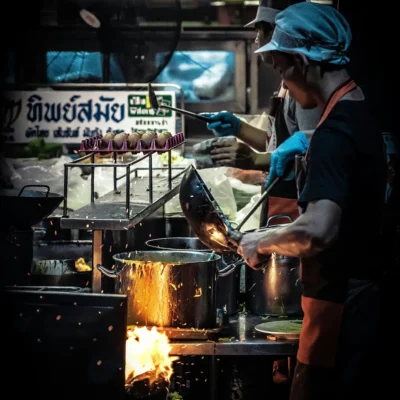 Street food chefs cooking over high heat at a Chiang Mai night market.